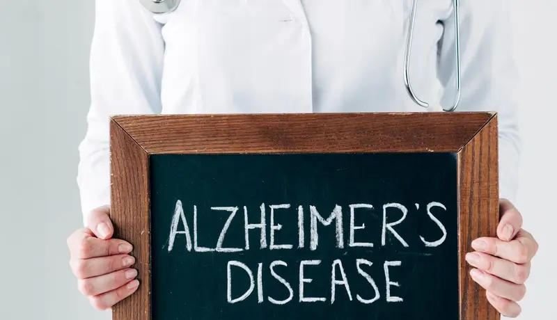 Γιατρός κρατάει πινακίδα που γράφει "Alzheimer's Disease"