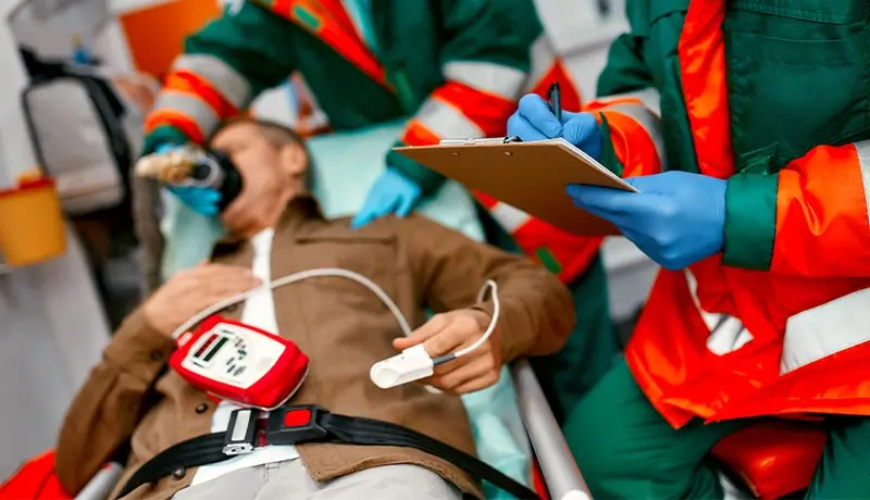 A wounded man receives emergency medical care from two paramedics equipped with emergency uniforms and gear.