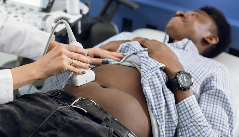 Doctor performing an abdominal ultrasound on a patient, focusing on the liver and gallbladder area.