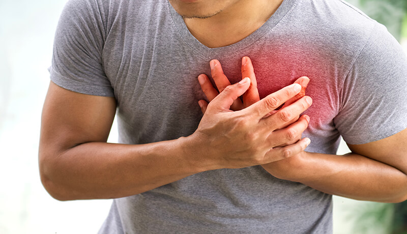 a man holding his left chest that is causing him pain Chest Back Pain Symptoms