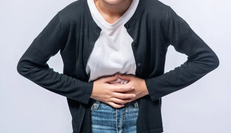 A woman standing with a stomach ache 