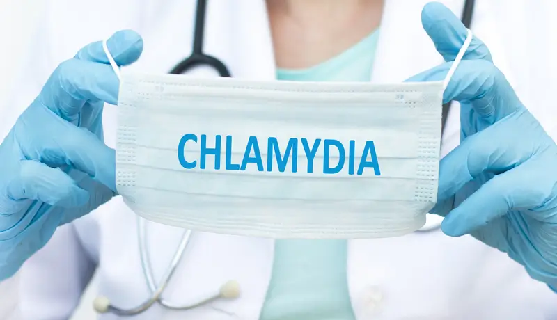 A doctor holding a mask which on the mask it says CHLAMYDIA