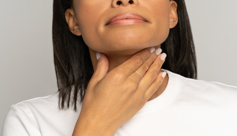 Closeup of woman touch sore throat. African female suffer from swallowing difficulty due to tonsilitis