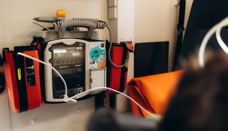 A portable cardiac monitor and defibrillator mounted on a wall, used for emergency heart care in critical situations.