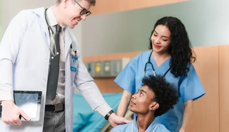 Doctor and nurse attending to a patient in a hospital room, providing compassionate care and discussing the patient’s health condition.