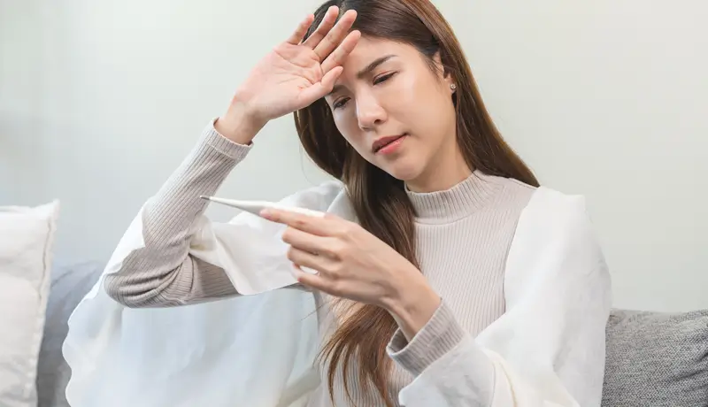 AA picture that shows a woman with fever holding her head
