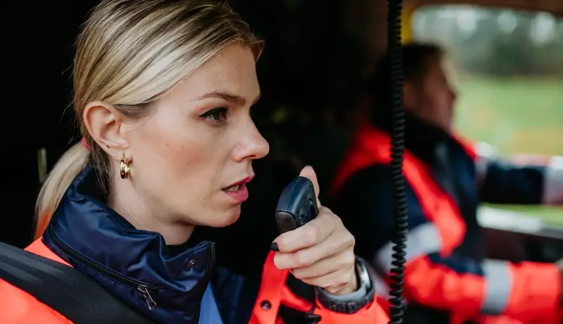 A female paramedic communicating via radio while in an emergency vehicle.