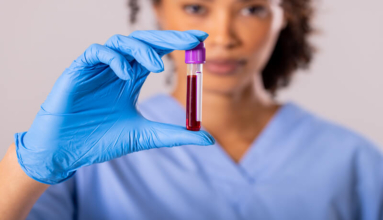 Portrait of african american mid adult female doctor wearing glove holding test tube with blood