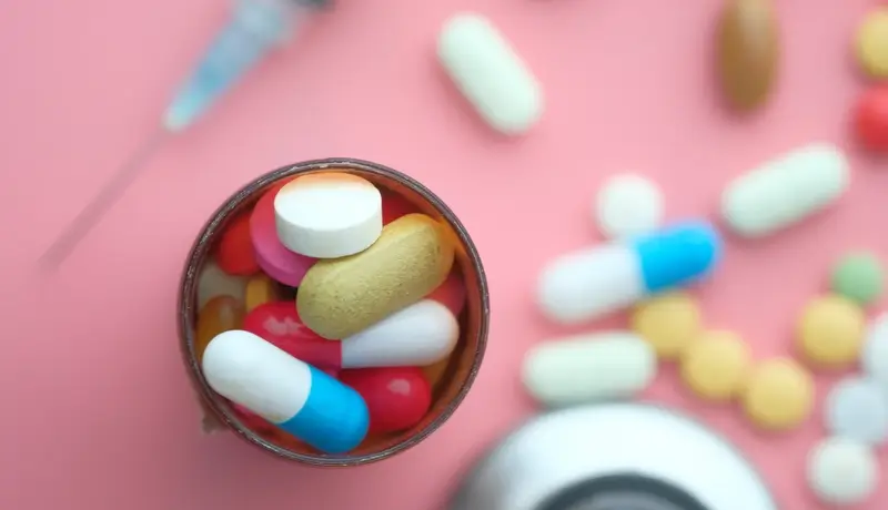 Several Types of Pills spilling out of a pill bottle
