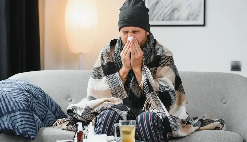 Sick man sits on couch at home