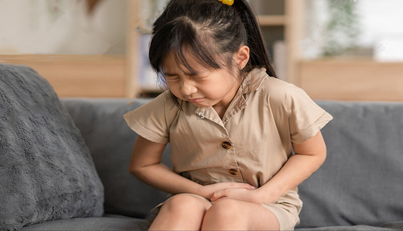 A child holding her belly cause she is in pain from Childhood UTI Treatment Prevention