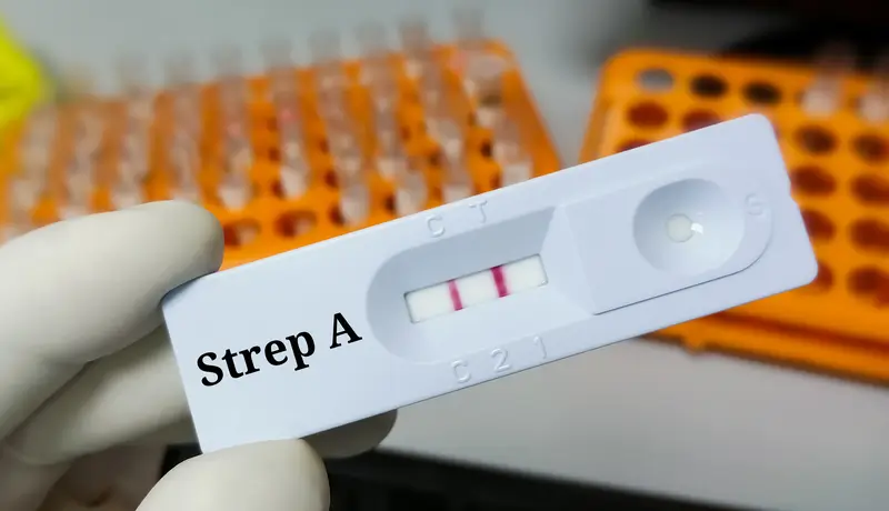 A picture showing a hand holding a positive rapid test